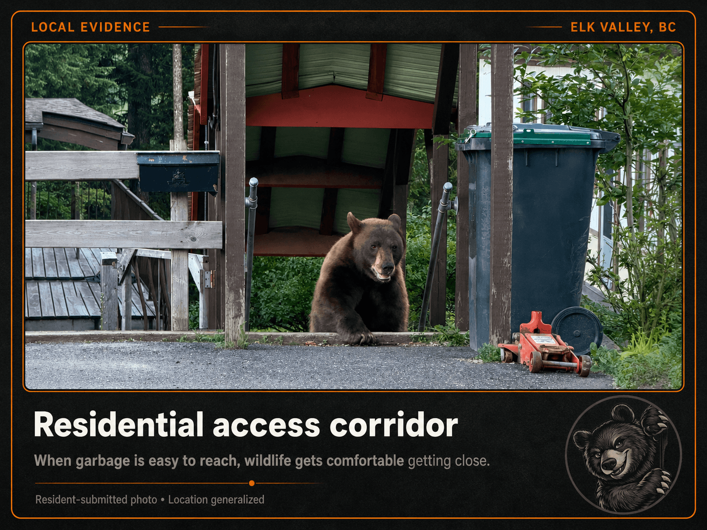 A bear sitting beside a garbage cart in a covered residential access corridor.